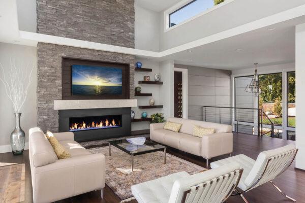 Beautiful living room in new modern  luxury home. Features vaulted ceilings, fireplace with roaring fire, clerestory windows, and hardwood floors